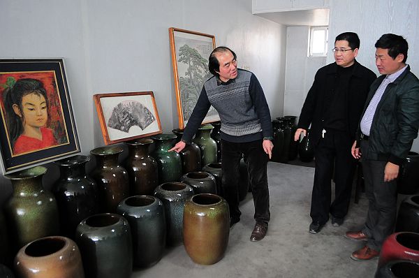 2013年3月6日，陶瓷雕刻绘画艺术家朱立民（左一）向客人介绍他制作烧制的大件陶瓷艺术品。.JPG