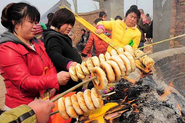 2013年3月16日，山东省茌平县韩屯镇罗屯村西北的鲁义姑庙会上，民众烤烧饼祈福求子。。.jpg